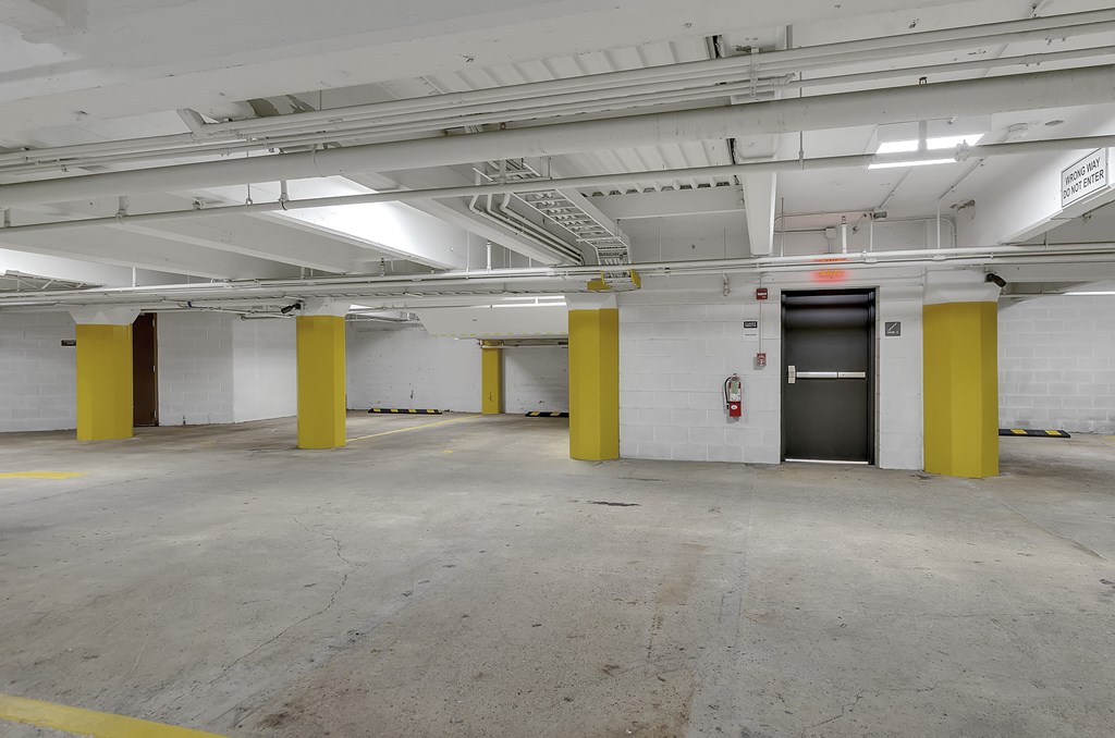 a parking garage with yellow pillars and a door at 100 South Apartments, Buffalo, 14202
