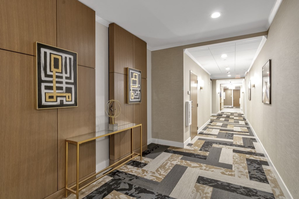 a long hallway with a carpet of geometric tiles and wood paneling at Nineteen North, Buffalo, 14202