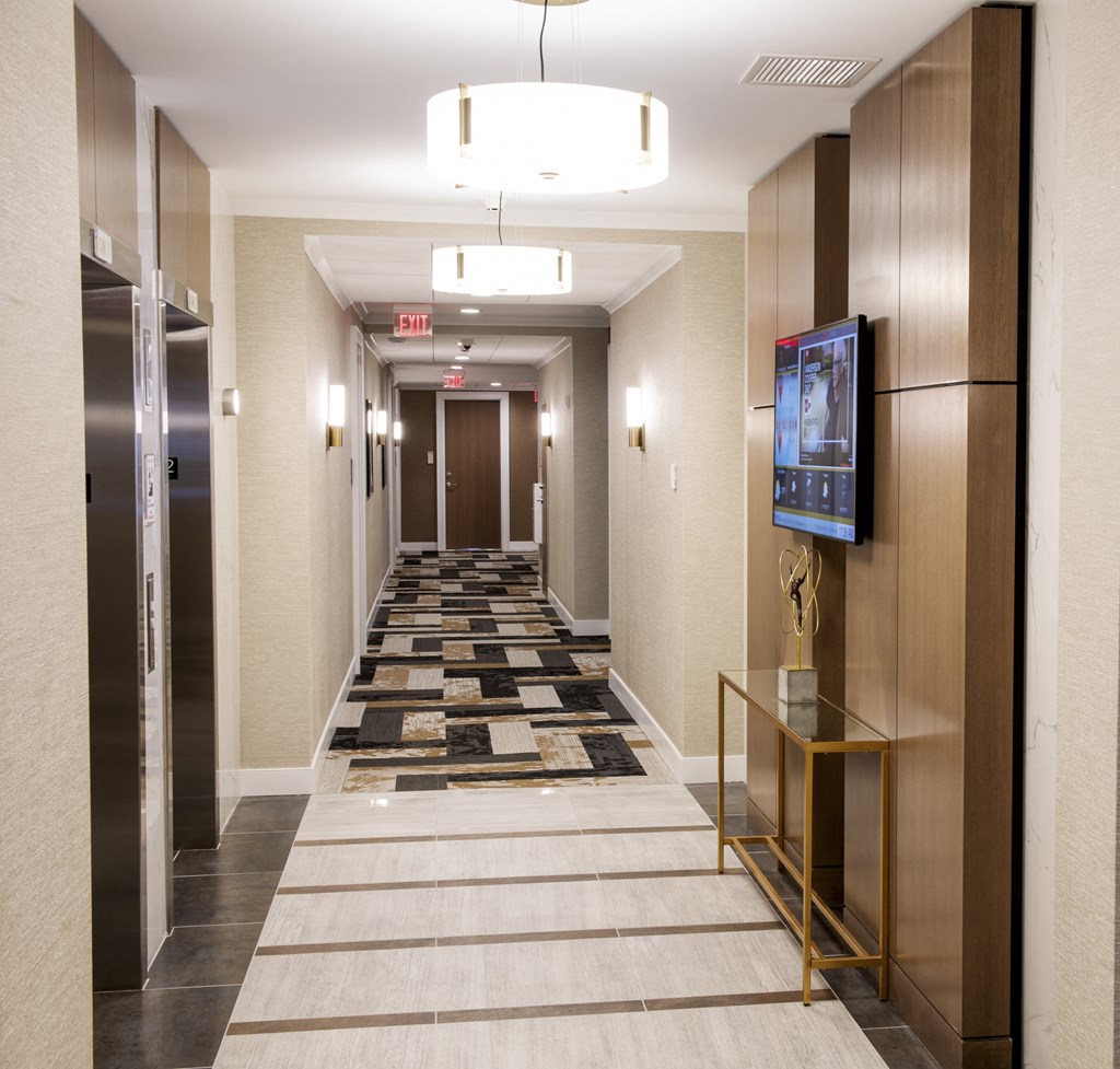 a long corridor with elevators and a carpeted hallway with a tv and elev at Nineteen North, New York