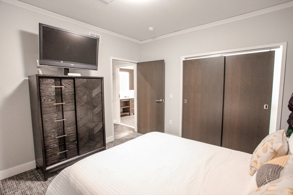 a bedroom with a bed and a tv on top of a cabinet