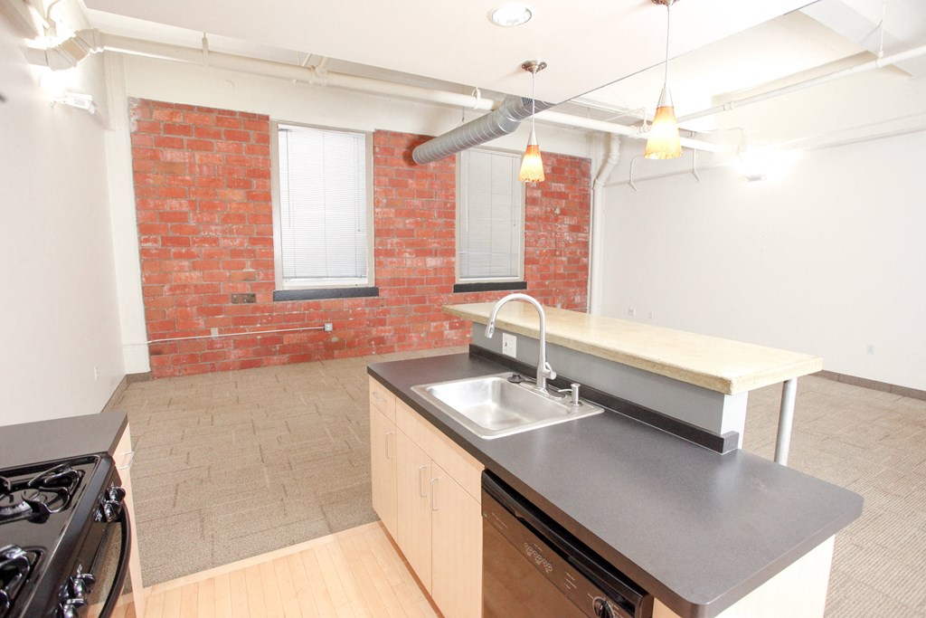 an empty kitchen with a sink and a red brick wall