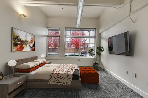 Modern bedroom with platform bed and wall mounted tv at The Lofts at Elk Terminal Apartments, New York