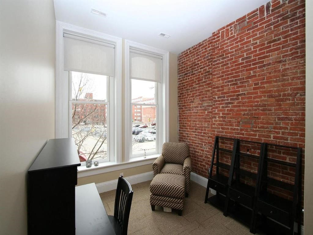 a room with a brick wall and a chair and a window