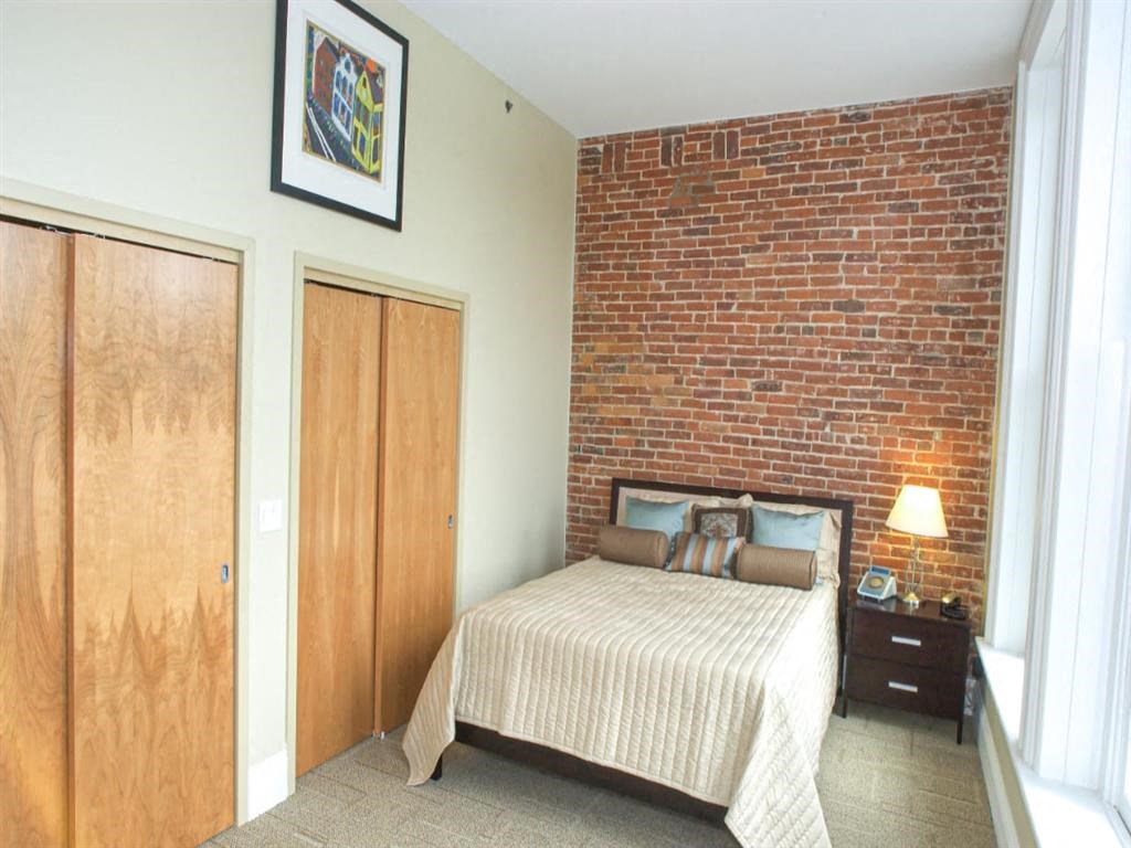 a bedroom with a bed and a brick wall