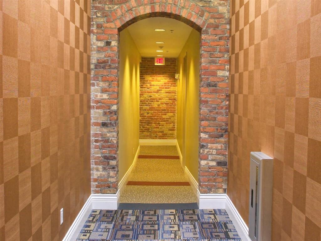 a hallway with a brick wall and a corridor with a yellow door
