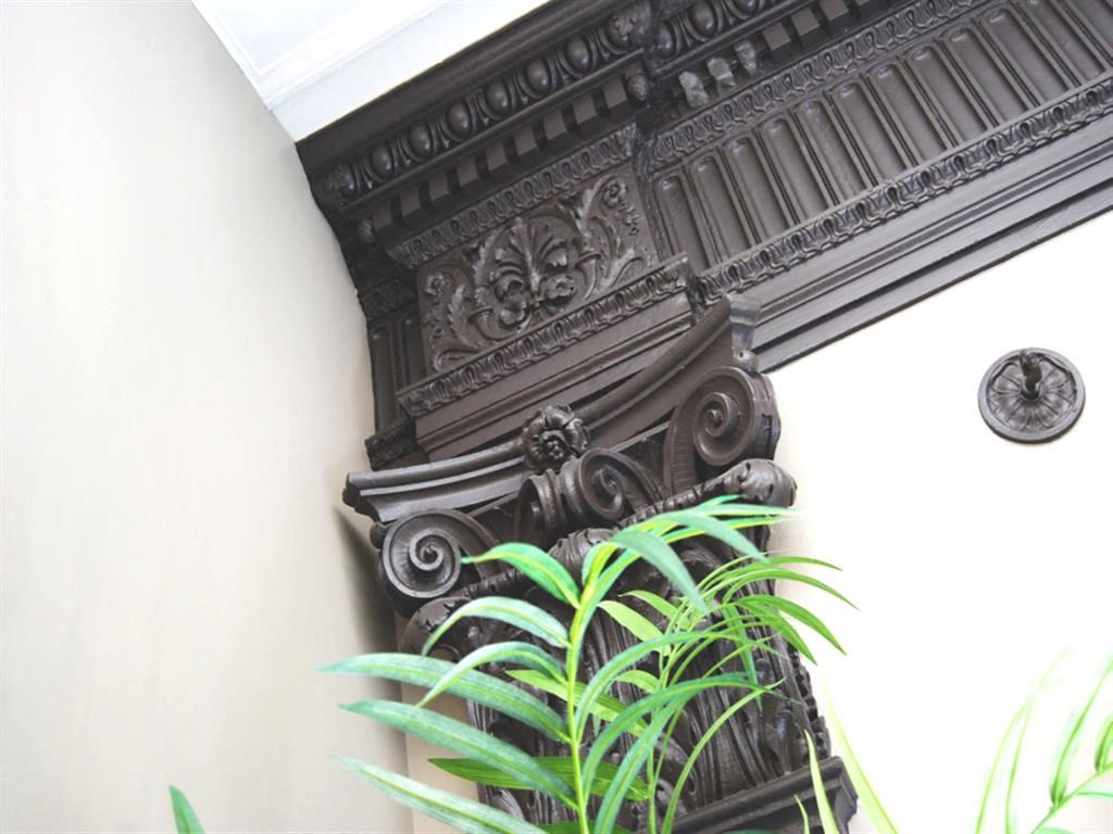 an ornate wooden column in a white wall with a plant