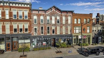 A street view of a row of buildings with a black car parked on the sidewalk.