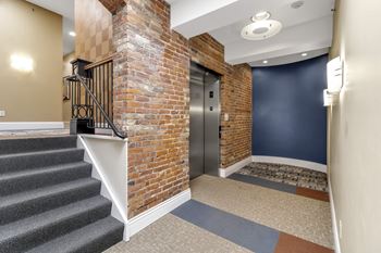 A hallway with a brick wall and a metal staircase.