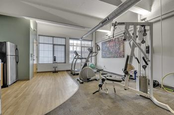 a gym with exercise equipment and a refrigerator in the corner at The Lofts at Elk Terminal, Buffalo, NY