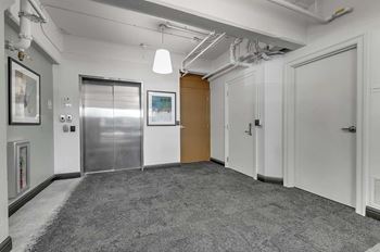 A room with a grey carpet and a wooden door.