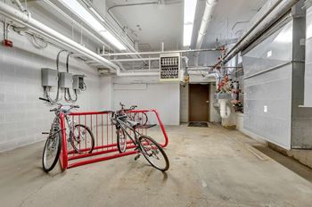Two bicycles are parked in a garage with a red bike rack.