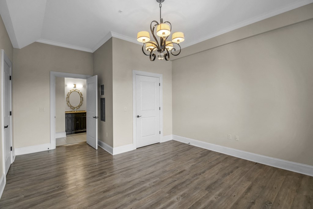 an empty living room with wood floors and a chandelier at The Knights @ 506 Delaware Apartments, Buffalo, 14202