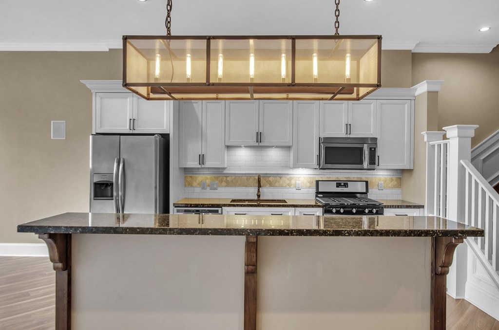 a kitchen with an island with a granite counter top and white cabinets at The Knights @ 506 Delaware Apartments, Buffalo, NY 14202