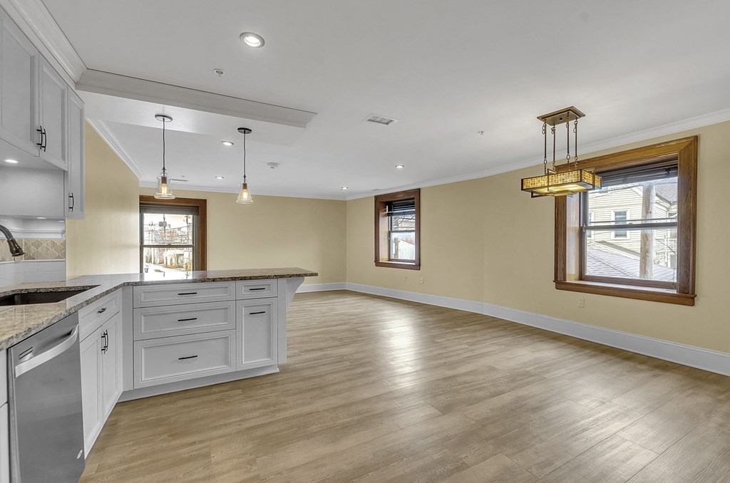 an open kitchen and living room with white cabinets and wood floors at The Knights @ 506 Delaware Apartments, New York, 14202