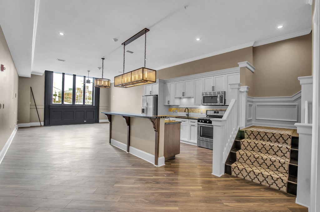 a large kitchen with white cabinets and a large island at The Knights @ 506 Delaware Apartments, New York