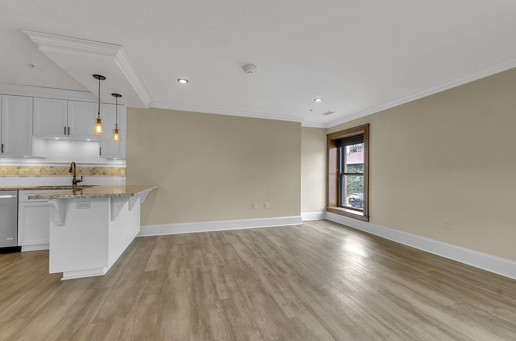 an empty living room with a kitchen and a window at The Knights @ 506 Delaware Apartments, Buffalo