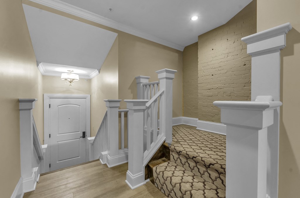 A staircase with a white railing and a brown carpeted stairway at The Knights @ 506 Delaware Apartments, Buffalo, New York