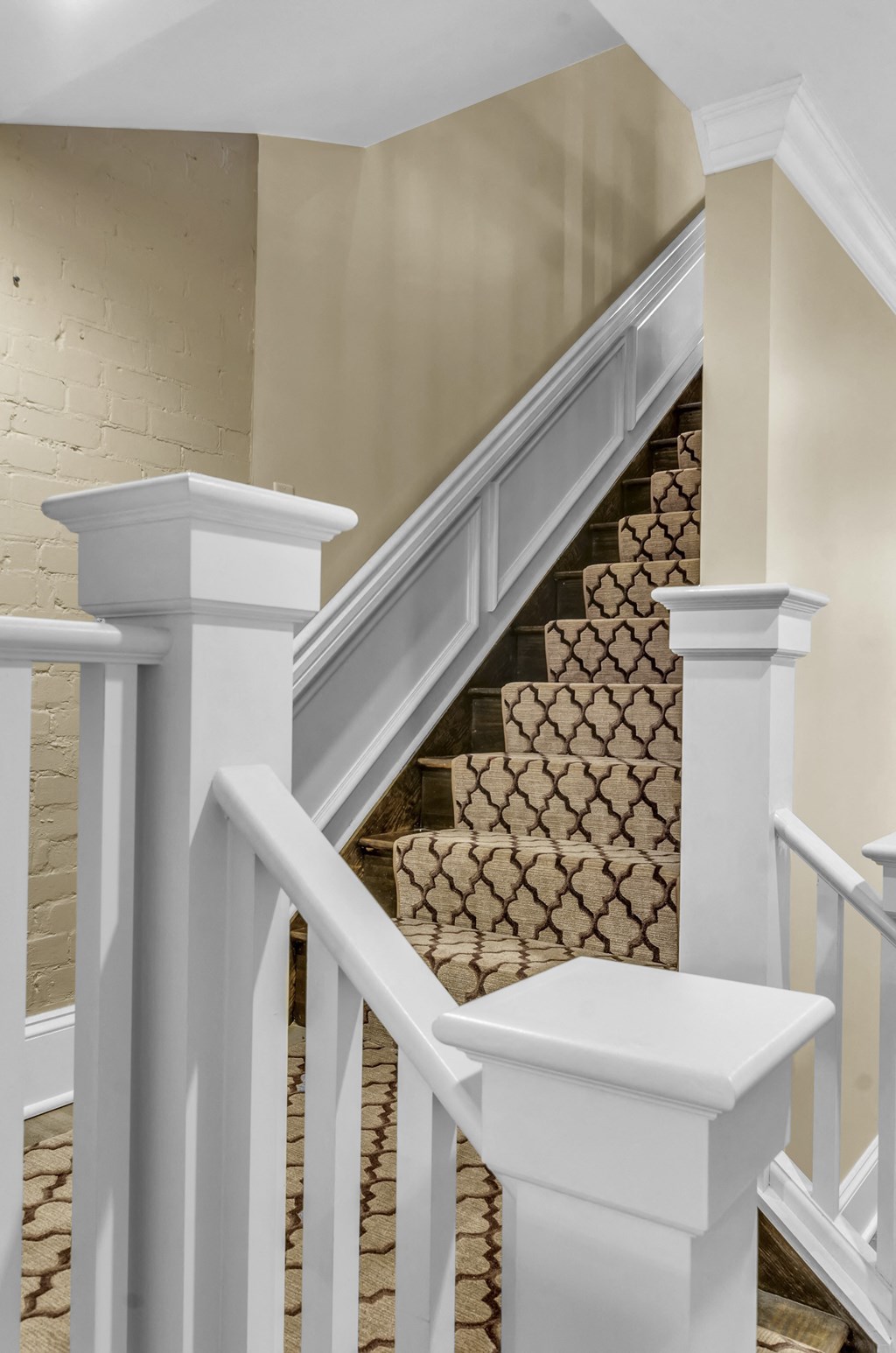 A staircase with a beige carpeted runner and white railings at The Knights @ 506 Delaware Apartments, Buffalo, NY