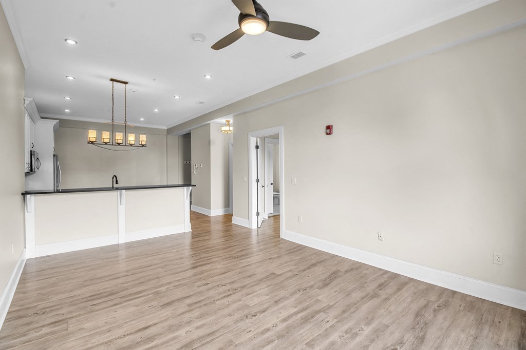 an empty living room with a ceiling fan and a kitchen at The Knights @ 506 Delaware Apartments, New York, 14202