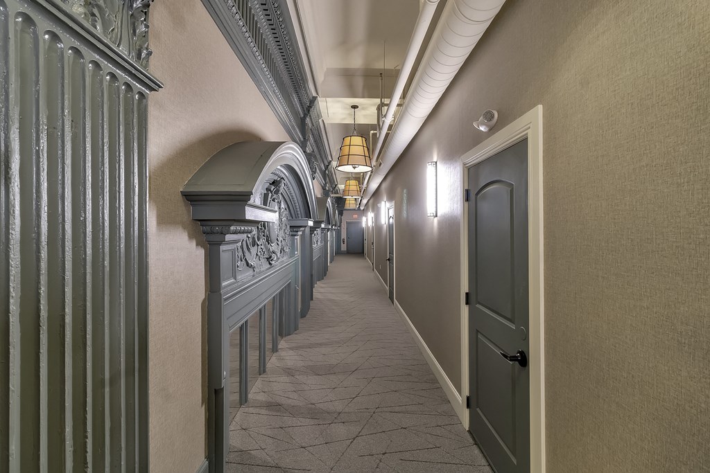 a long hallway with a door and columns on the side at The Knights @ 506 Delaware Apartments, New York, 14202
