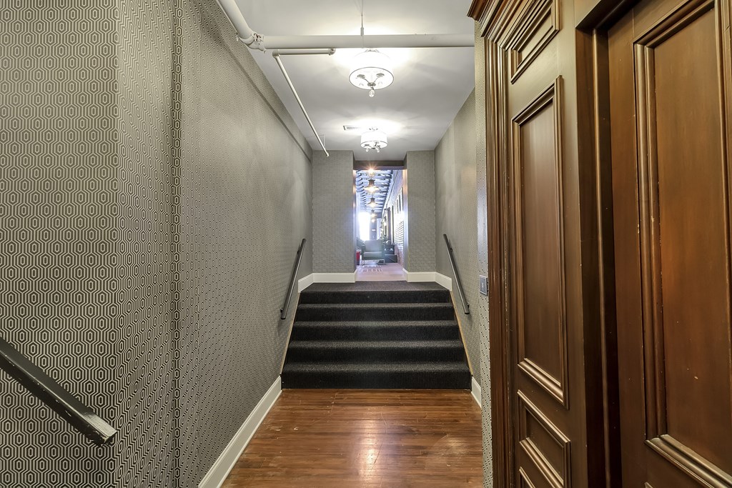 a long hallway with stairs and wood flooring and a hallway with doors and stairs at The Knights @ 506 Delaware Apartments, Buffalo, 14202