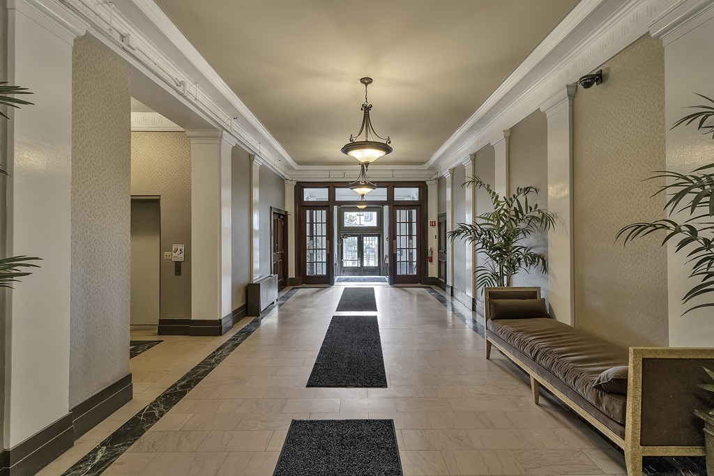a hallway with a bench and plants and a chandelier at The Knights @ 506 Delaware Apartments, New York