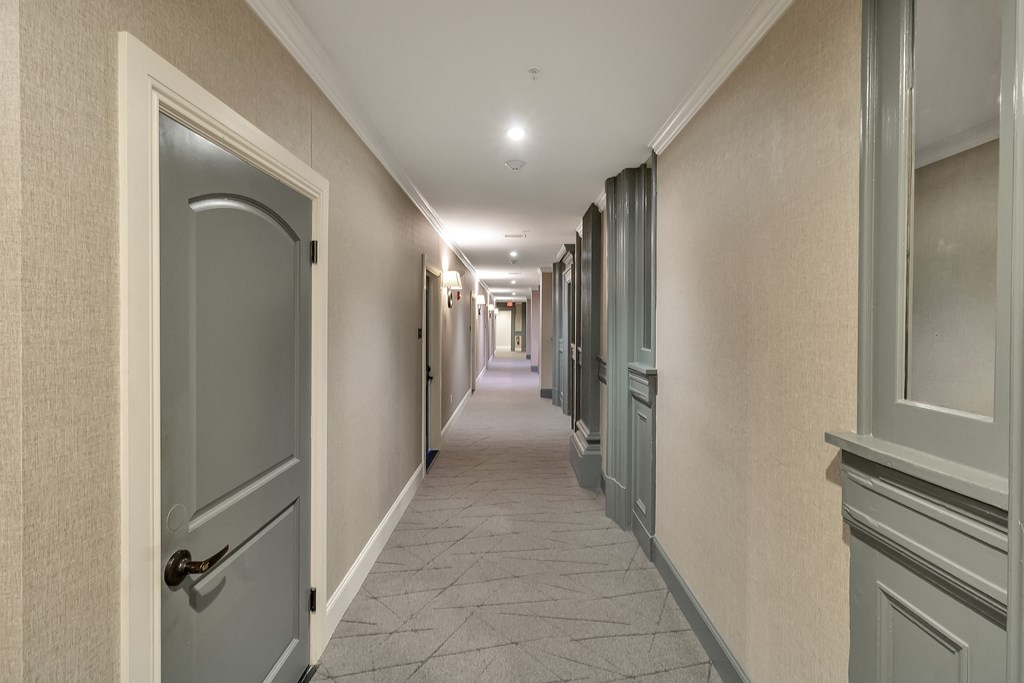a hallway with blue doors and white walls and a tiled floor at The Knights @ 506 Delaware Apartments, Buffalo, 14202