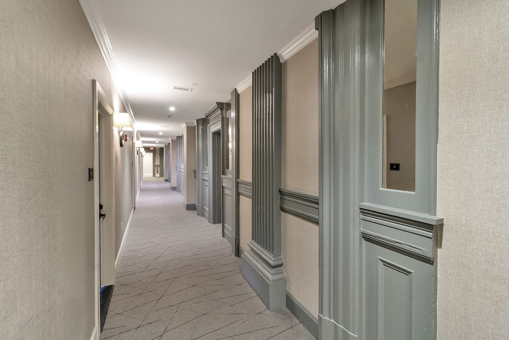 a long hallway with gray doors and white walls at The Knights @ 506 Delaware Apartments, Buffalo, New York