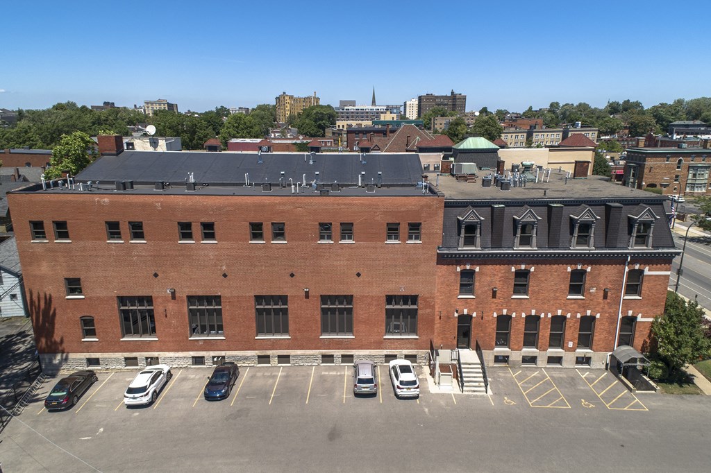 an aerial view of a brick building with cars parked in front of it at The Knights @ 506 Delaware Apartments, Buffalo, 14202