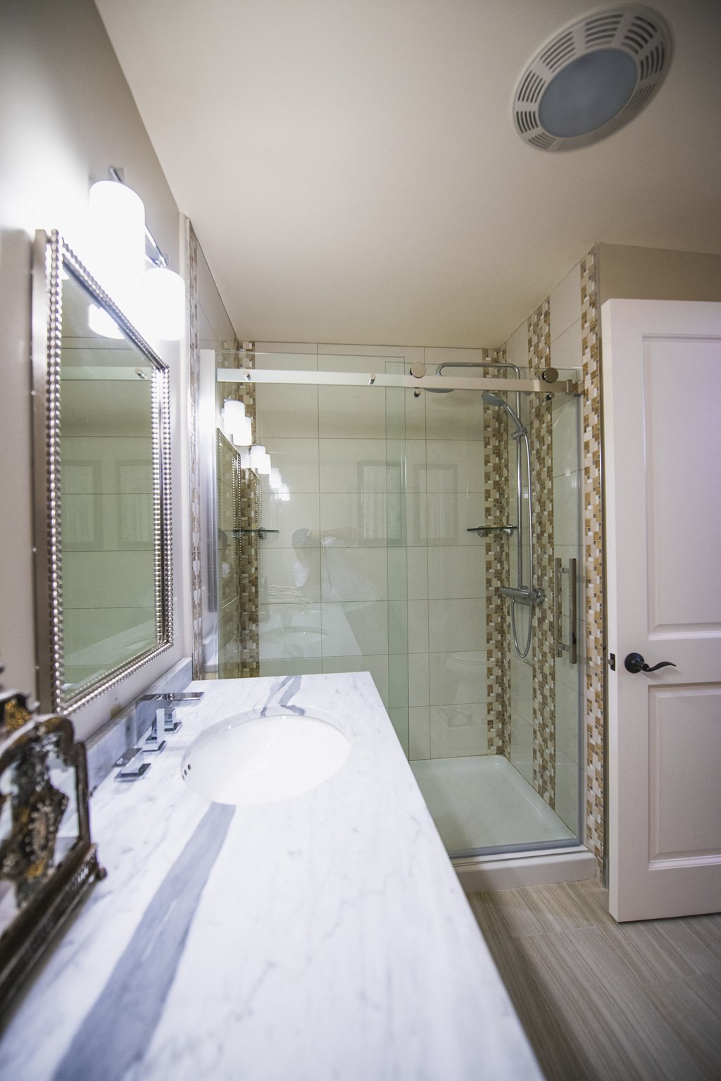 a bathroom with a shower and a sink and a mirror at The Knights @ 506 Delaware Apartments, New York, 14202