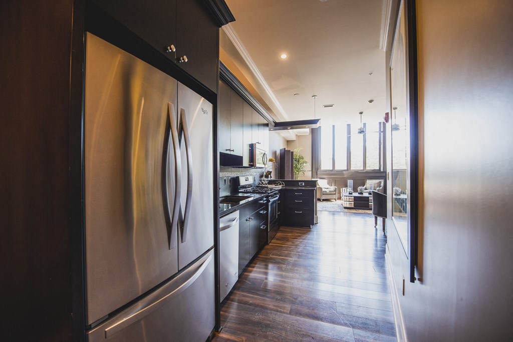 a large kitchen with stainless steel appliances and a wooden floor at The Knights @ 506 Delaware Apartments, Buffalo, 14202