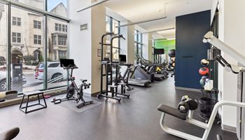 a gym with weights and cardio machines and a large window
