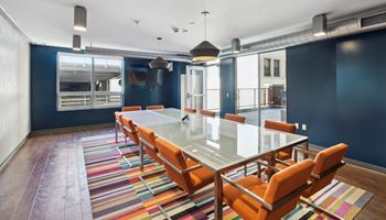a conference room with a glass table and orange chairs
