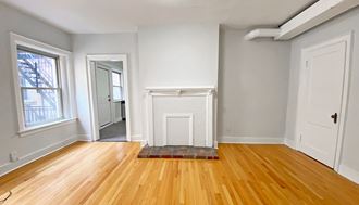 an empty living room with a fireplace and hardwood floors