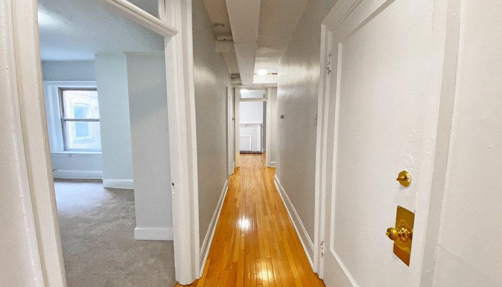 a hallway with white walls and wood floors