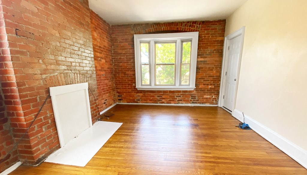 an empty room with wood floors and a window