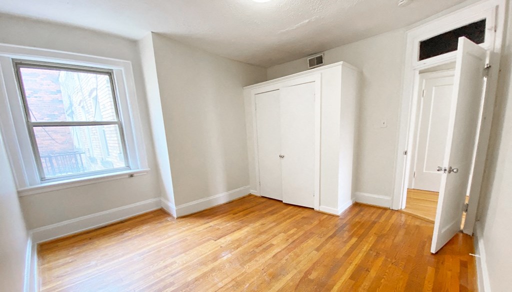 an empty room with hardwood floors and a large window