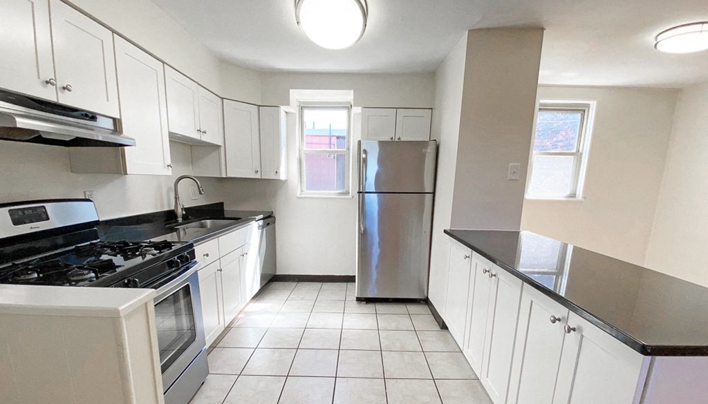 a kitchen with white cabinets and black countertops