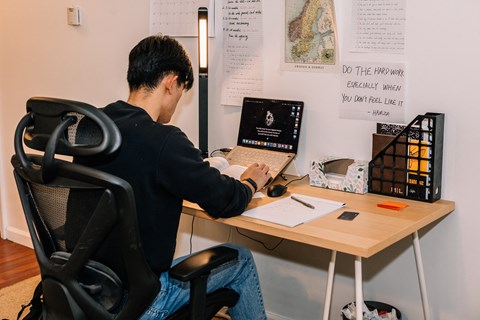 a man sitting at a desk with a laptop at University Commons Apartments, Oakland, Pittsburgh