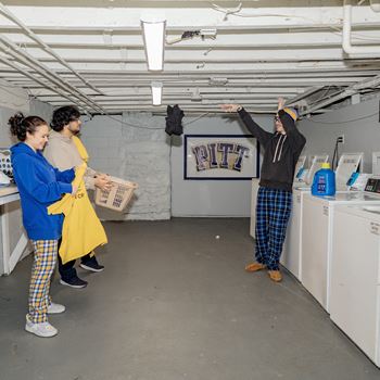 a man in a yellow raincoat points at something on the ceiling while two people look on at University Commons Apartments, Oakland, Pittsburgh