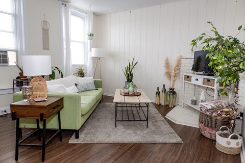 a living room with white walls and a green couch at University Commons Apartments, Oakland, Pittsburgh