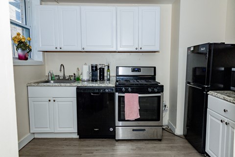 a kitchen with white cabinets and black appliances at University Commons Apartments, Oakland, Pittsburgh