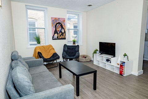 a living room with a couch coffee table and chairs and a tv on a stand at University Commons Apartments, Oakland, Pittsburgh
