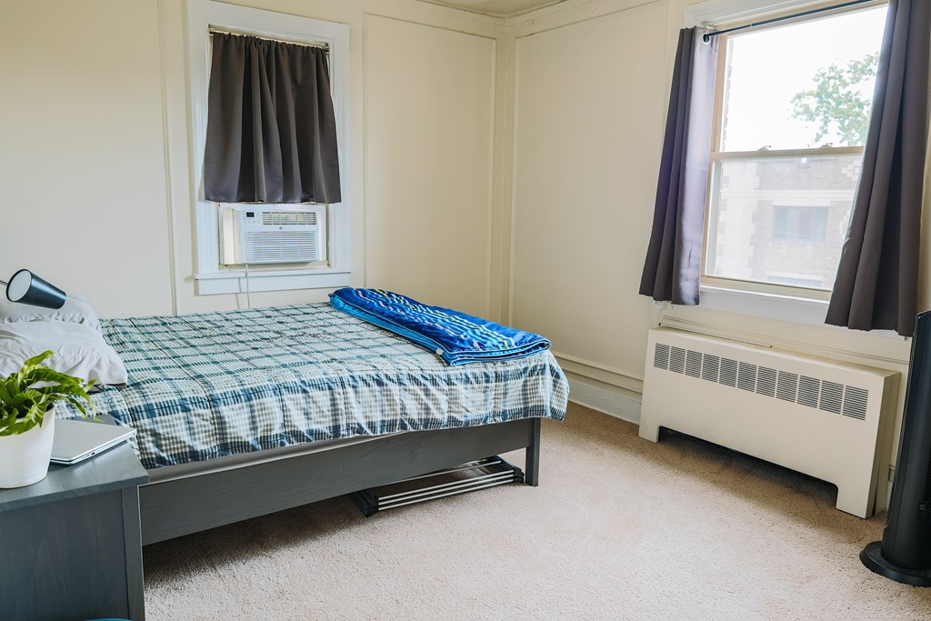A bedroom with a bed, nightstand, and window.