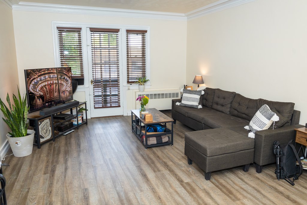 A living room with a brown couch and a wooden floor.