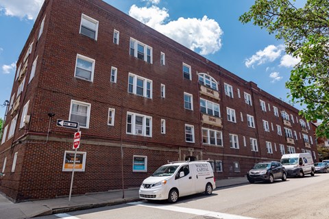 A white van is parked on the street in front of a brick building.