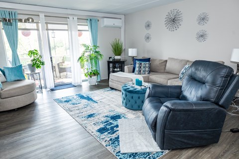 A living room with a blue rug and a black leather sofa. at Walnut Crossings, Monroeville, PA, 15146