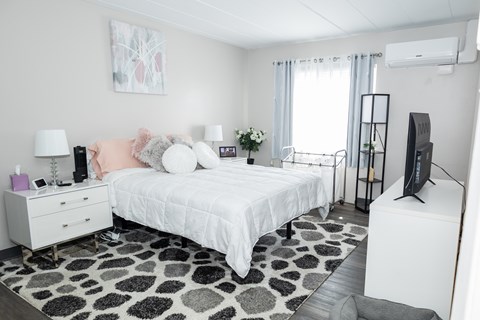 A bedroom with a white bed, a white dresser, and a black and white rug. at Walnut Crossings, Monroeville, PA, 15146