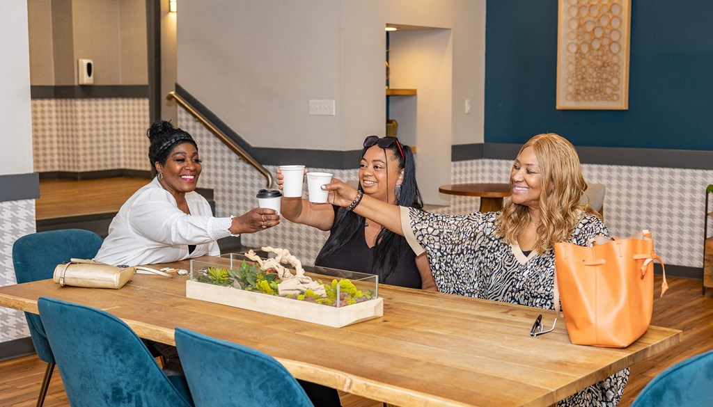 three women sitting at a table drinking coffee