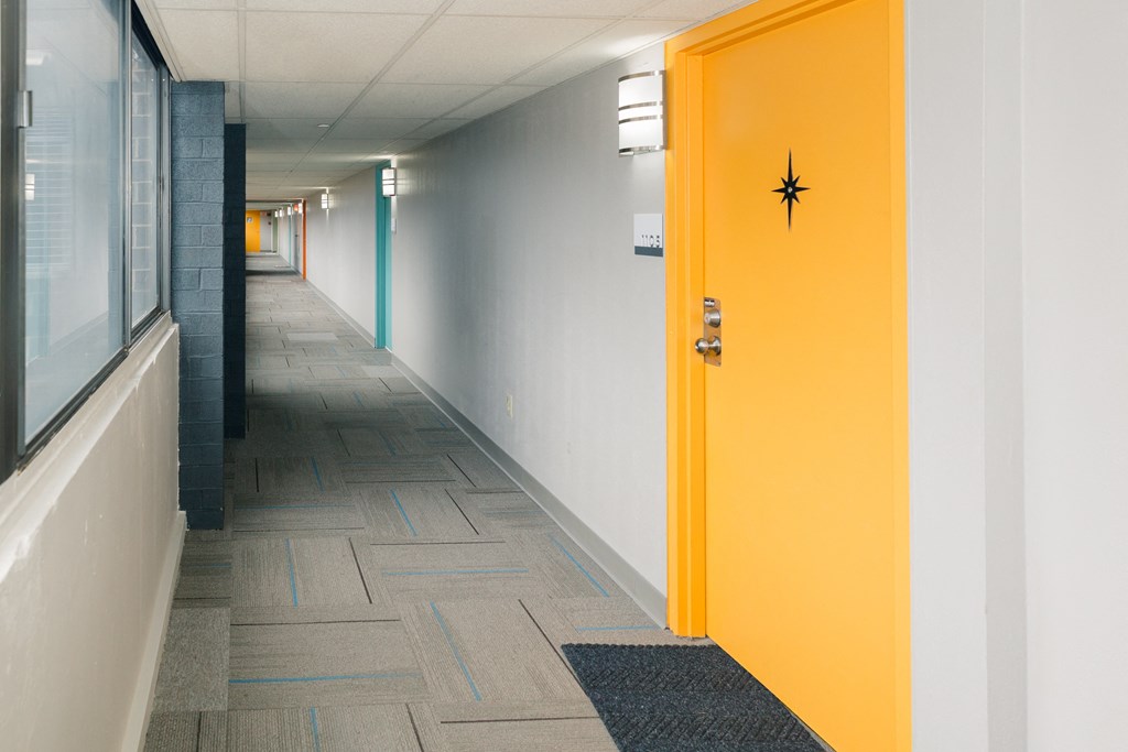 A hallway with a yellow door and a black doorknob at Walnut Towers at Frick Park, Pittsburgh